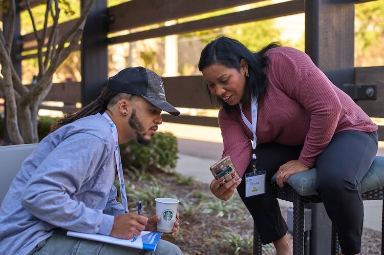 Devon Wilson talking and looking over a phone together with a food advocate.